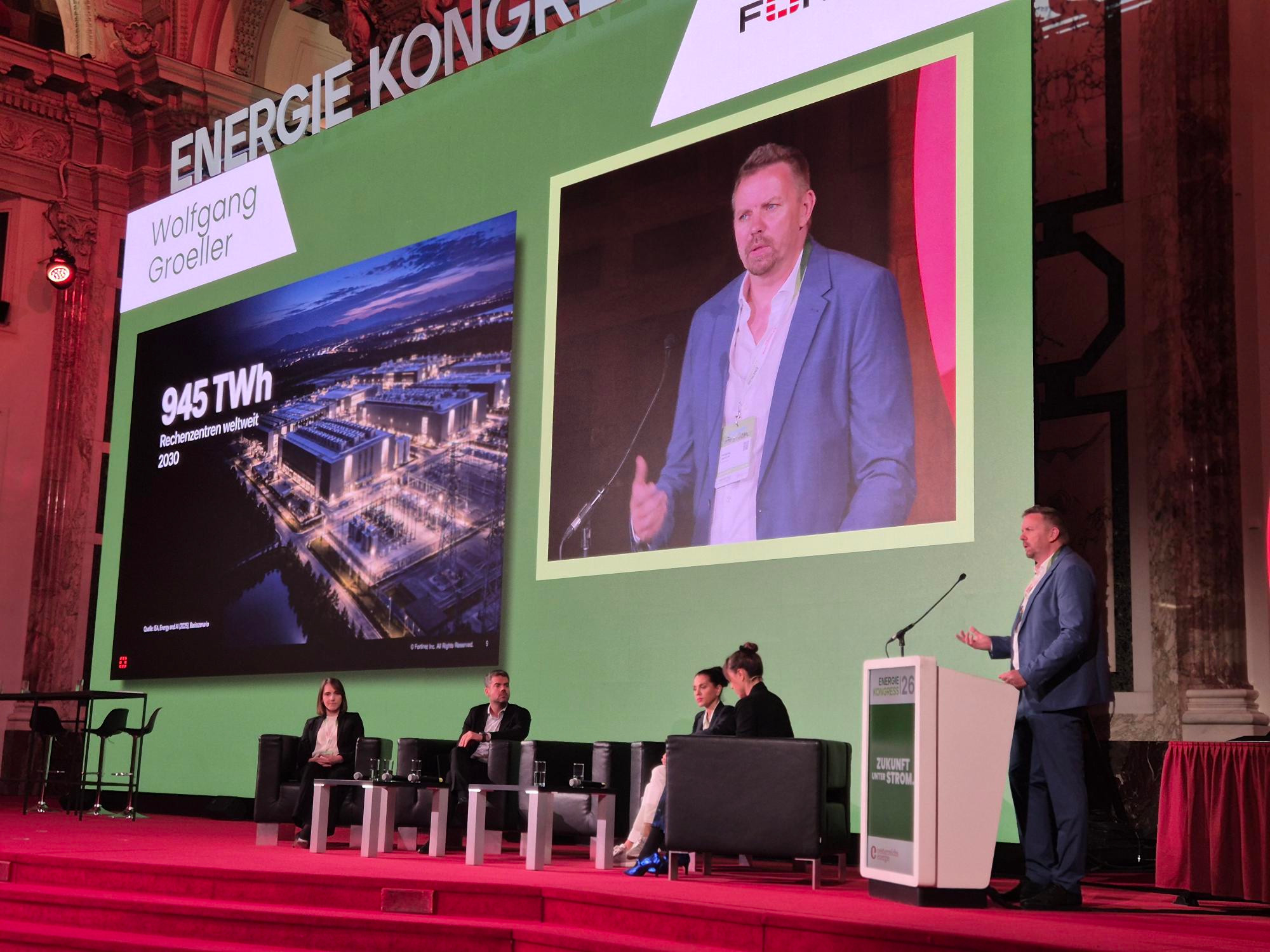 Wolfgang Gröller beim Energiekongress am Rednerpult, neben einer großen Projektion zu KI und Energie